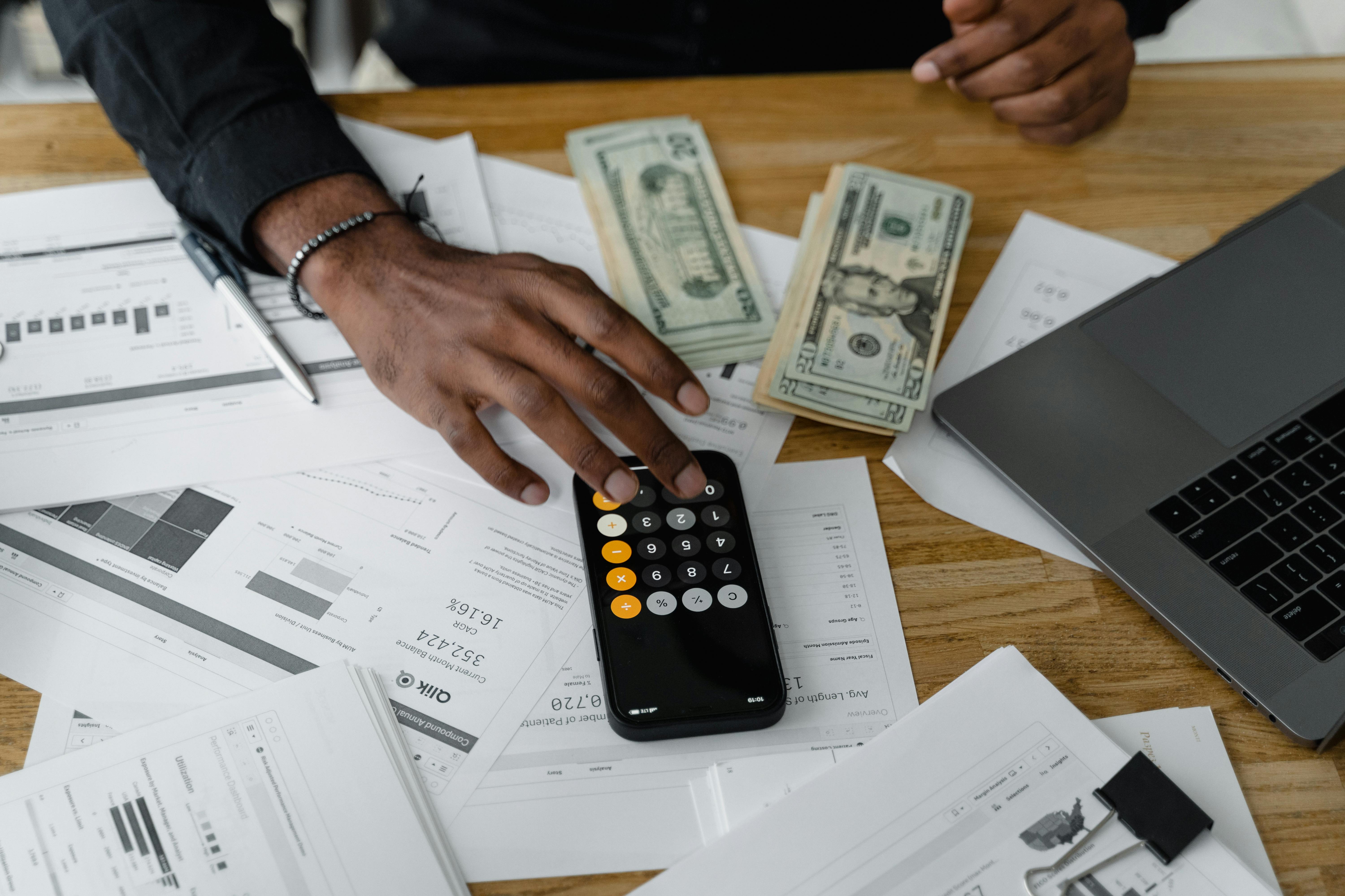 Trabajo contable en proceso: calculadora, documentos y efectivo sobre un escritorio